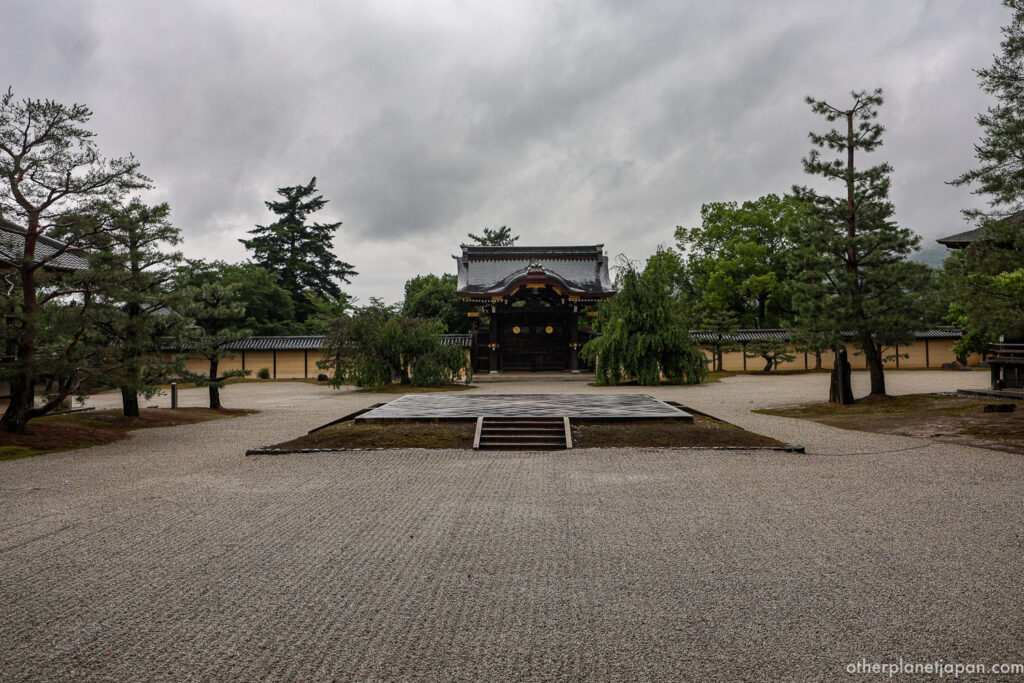 The Chokushimon gate of Daikakuji Temple framed by pine trees and a vast expanse of raked white gravel under overcast skies in Kyoto