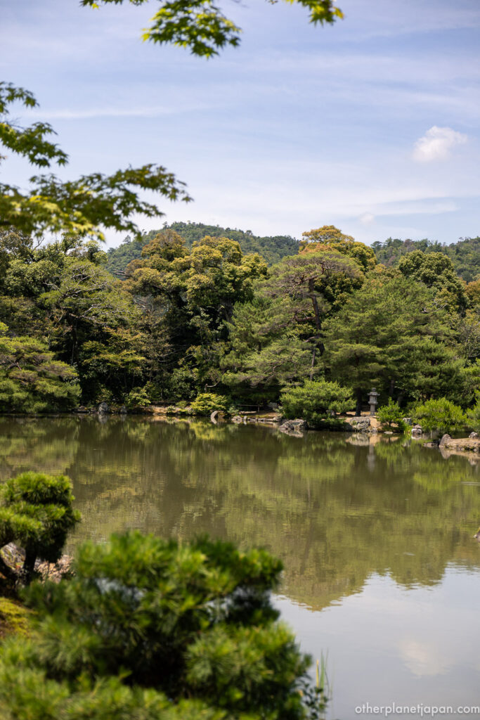 Kyoko-chi pond and surrounding pine trees with distant hills at Kinkakuji temple grounds, Kyoto