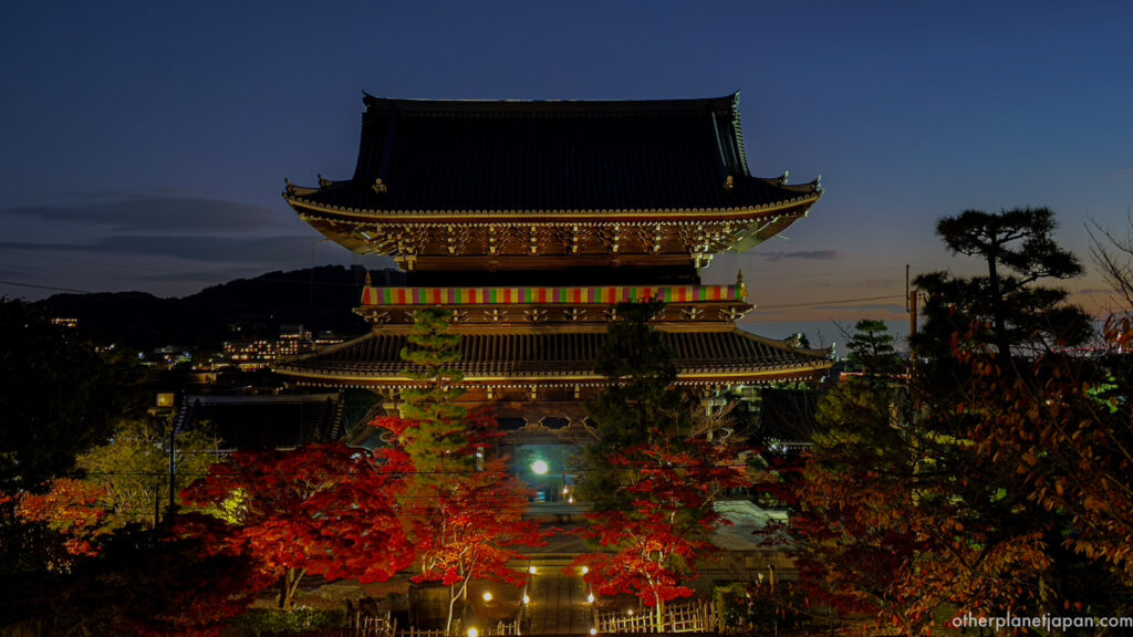 Sanmon gate of Konkai-komyoji illuminated at night during the autumn light-up with glowing red maples