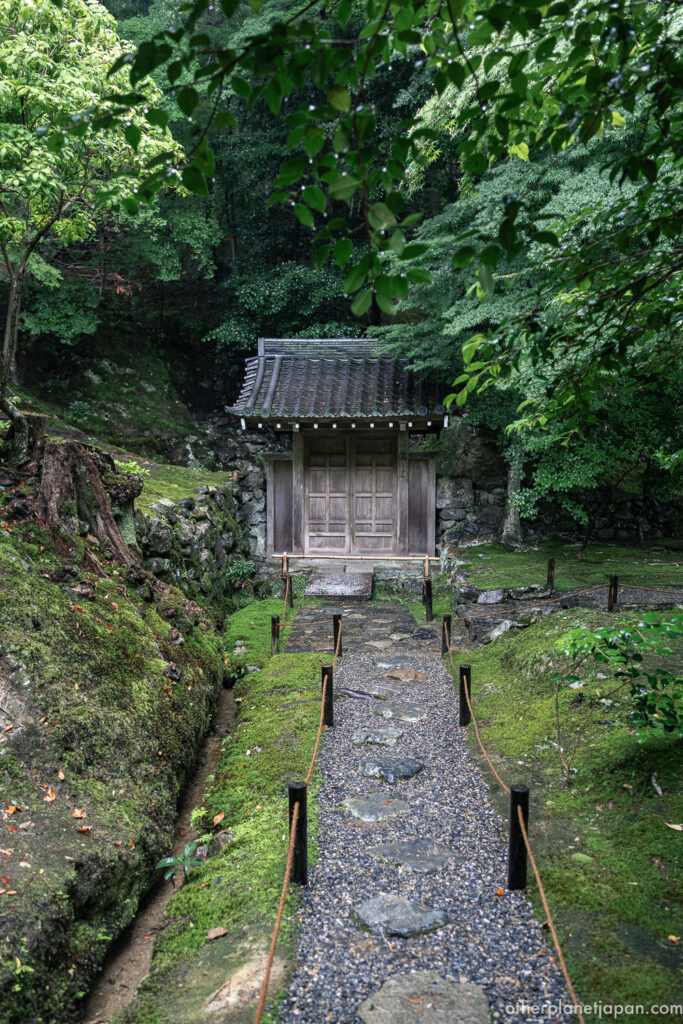 Small wooden gate set into a moss-covered stone wall, leading to the restricted upper garden at Saihō-ji