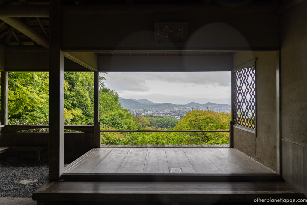 View of Kyoto city framed by a wooden pavilion opening at Okochi Sanso garden