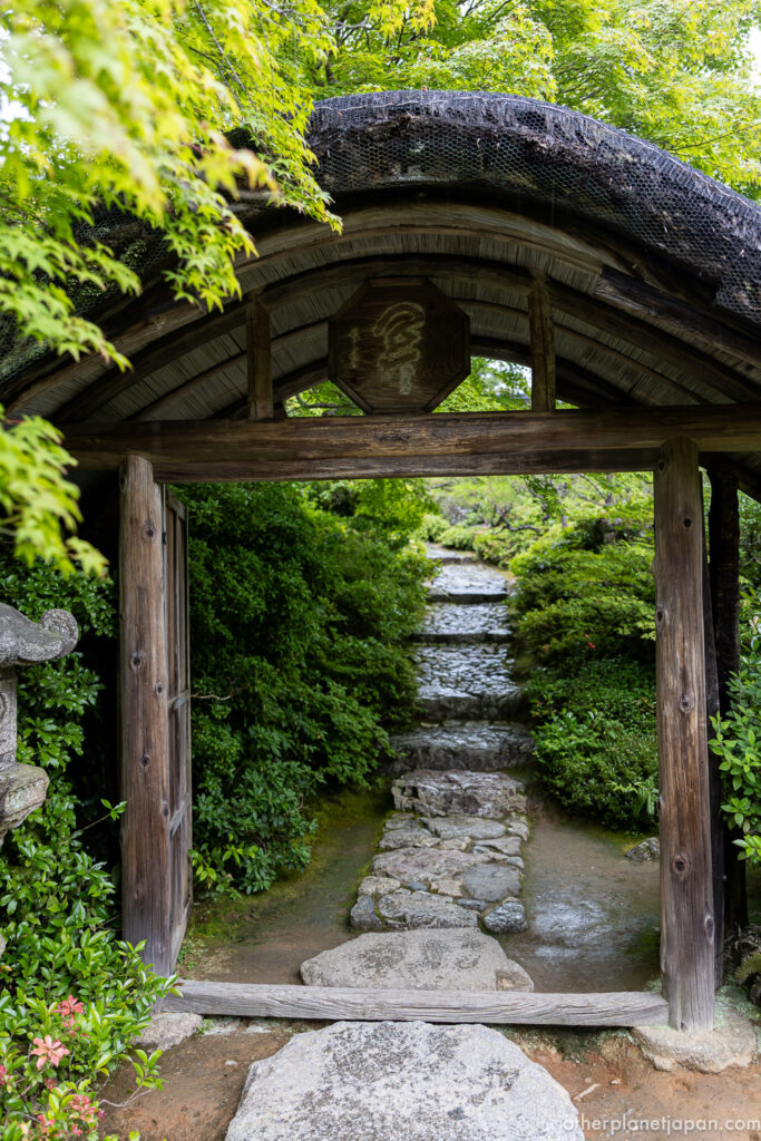Moss-covered traditional gate and stone steps at the entrance to Okochi Sanso garden, Kyoto