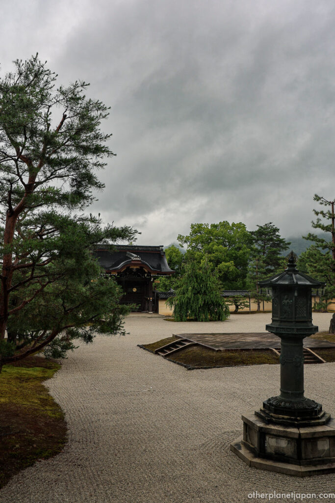 A moss-covered stone lantern beside raked gravel in a tranquil Zen garden at Daikakuji Temple, Kyoto