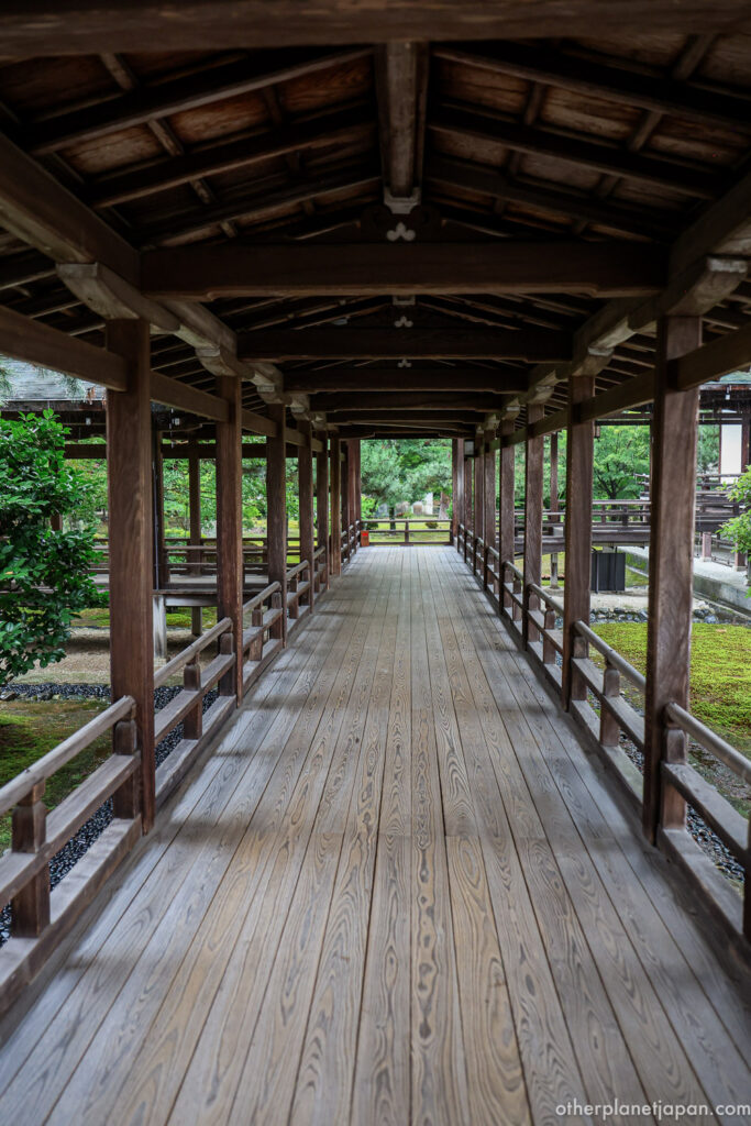 A symmetrical covered wooden corridor stretching into the distance at Daikakuji Temple, with gardens and moss visible on both sides