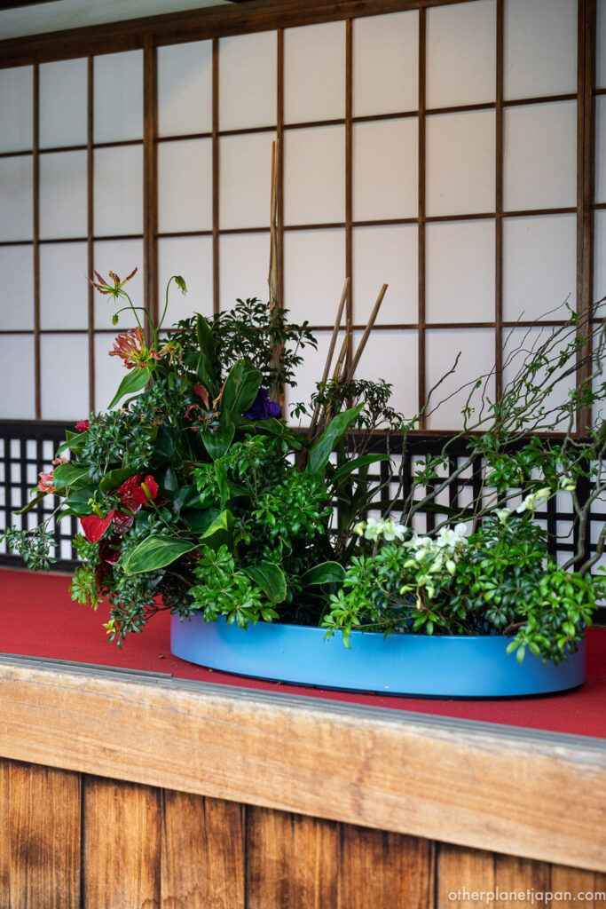 A Saga Goryu ikebana flower arrangement in a blue vessel displayed against shoji paper screens at Daikakuji Temple