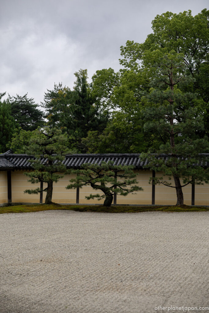 A Zen rock garden with a stone lantern and raked white gravel bordered by temple walls at Daikakuji in Kyoto