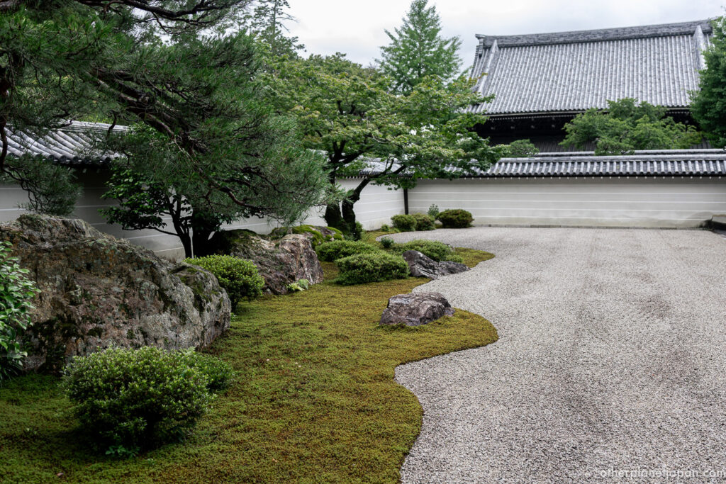 The wide karesansui rock garden of Nanzenji Hojo, with raked white gravel, dark stones, and a pine tree along the back wall in Kyoto.