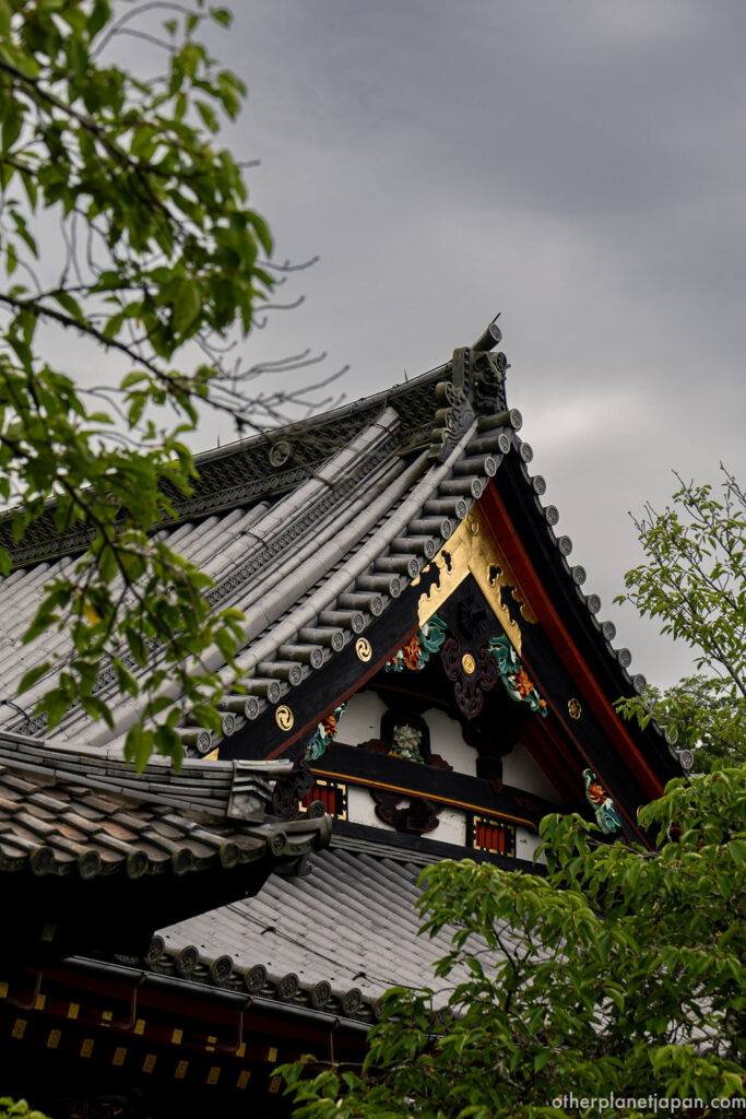 Close-up of colorful carved gable ornaments on the tiled roof of Bishamondo Temple, Kyoto