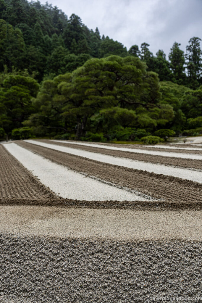The raked ginshadan sand sea at Ginkakuji stretching toward a green forested hillside, Kyoto"