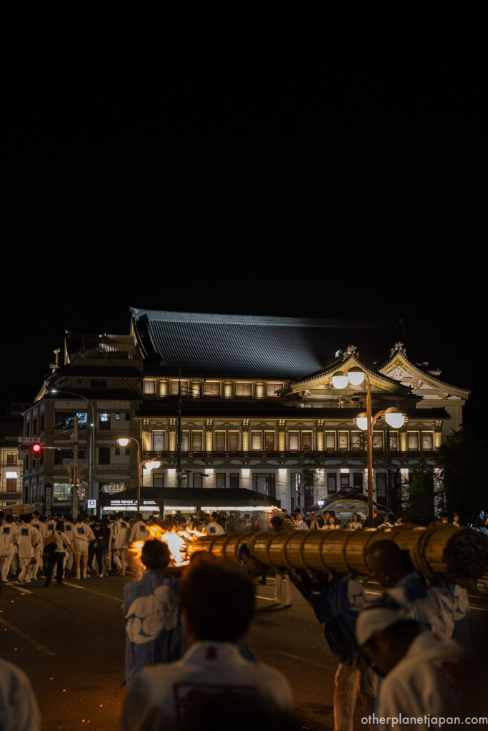 The great taimatsu torch carried on men's shoulders past the illuminated Minamiza Theater at night