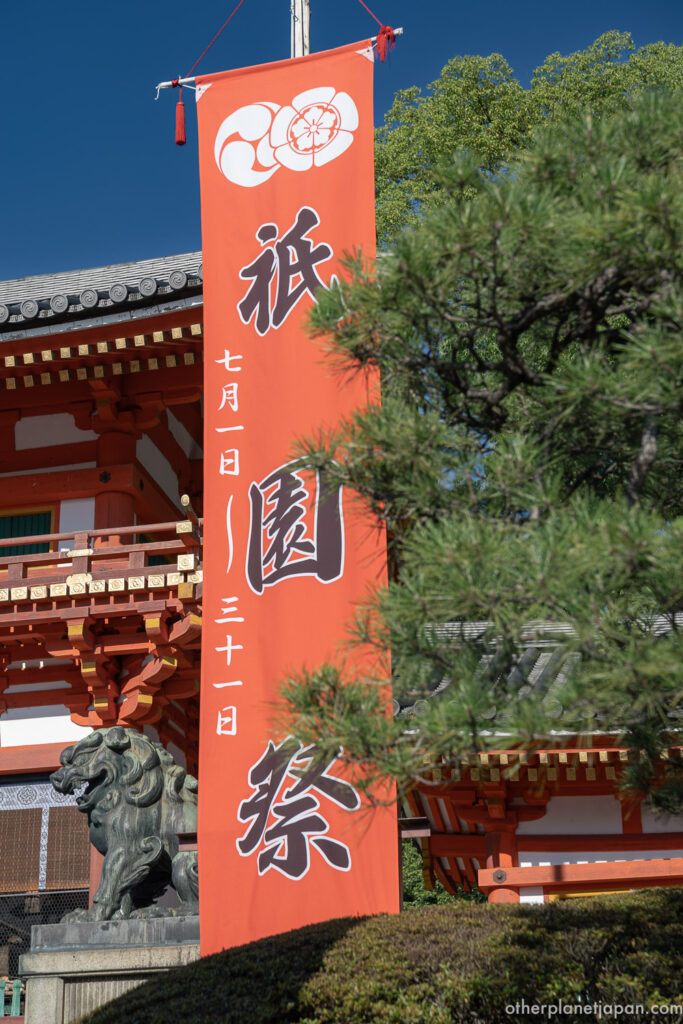 Orange Gion Matsuri banner at Yasaka Shrine announcing the festival runs July 1 through 31