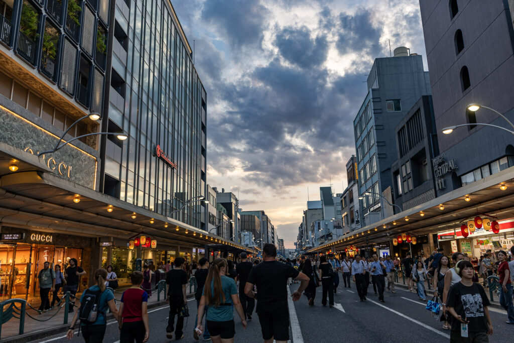 Shijo Street closed to traffic and filled with pedestrians at dusk during Gion Matsuri Yoiyama in Kyoto