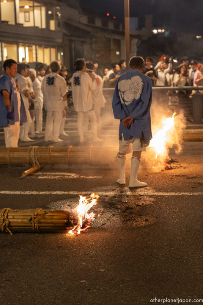 Bundled bamboo torches burning on the pavement of Shijo-dori during the Mikoshi Arai