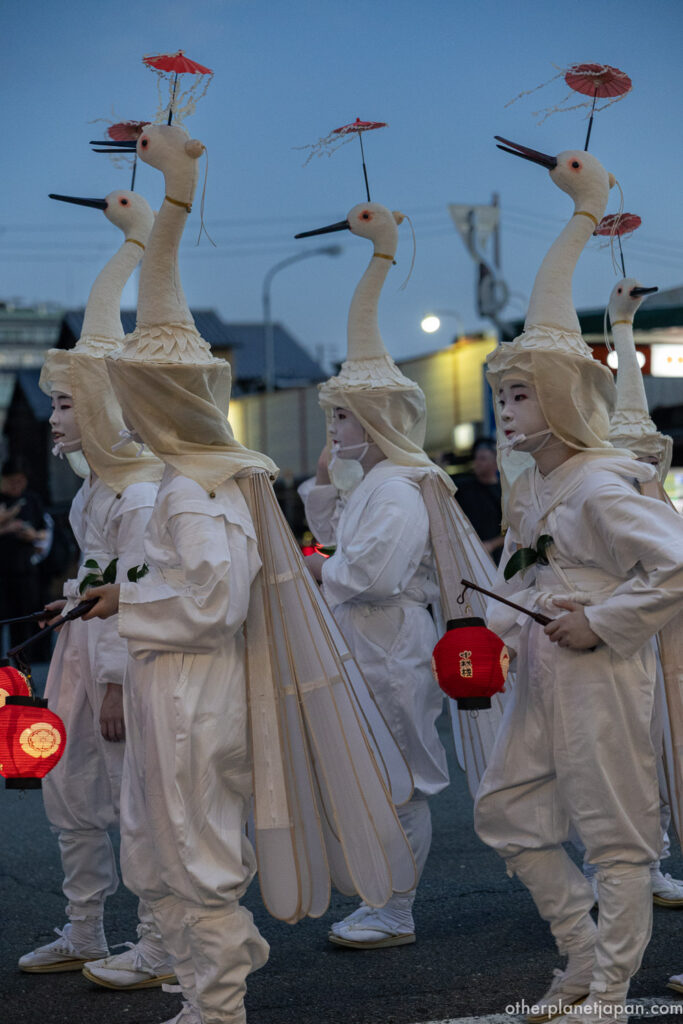 Sagi Odori heron dancers in white costumes with beaked headdresses and folded wings