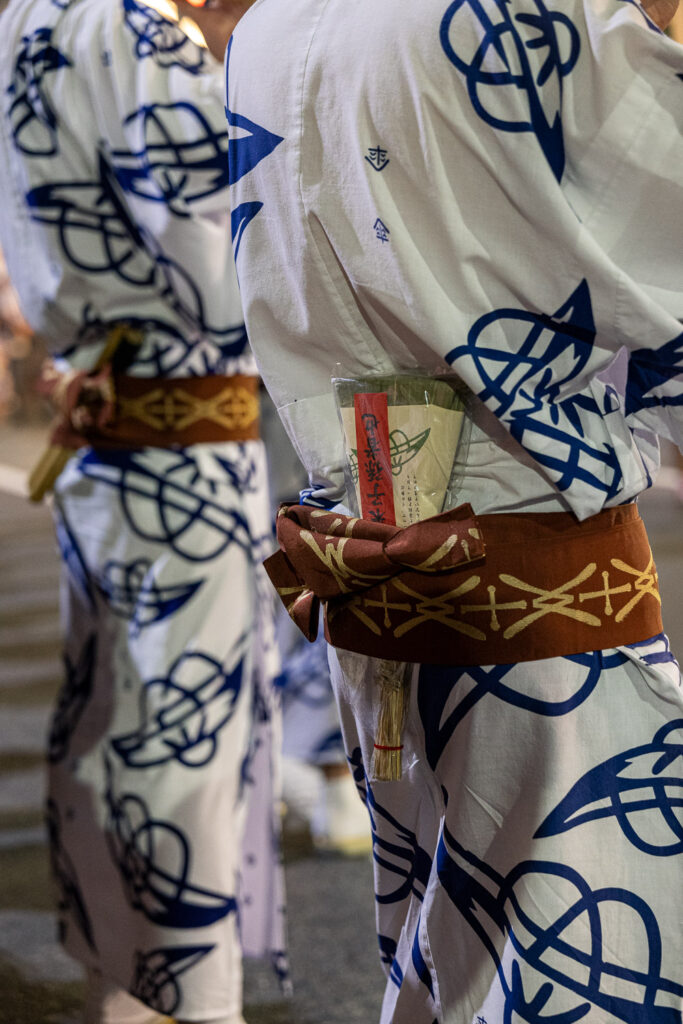 Detail of festival yukata with indigo patterns and a folding fan tucked into a brown obi sash at Gion Matsuri