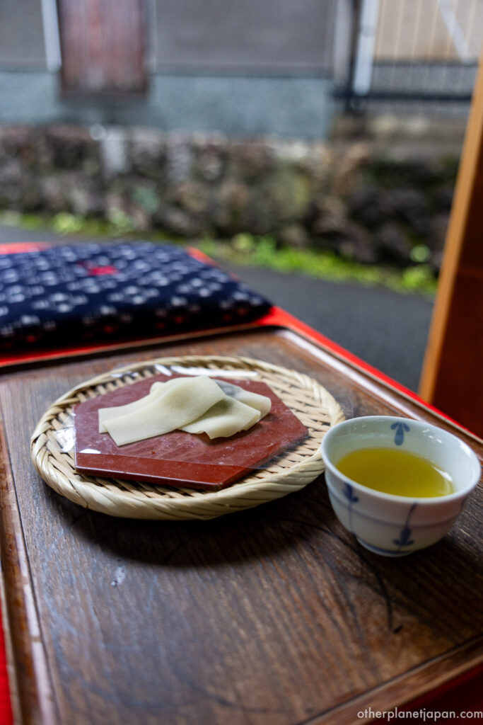 A plate of handmade raw yatsuhashi sheets beside a cup of green tea at a teahouse near Ginkakuji, Kyoto