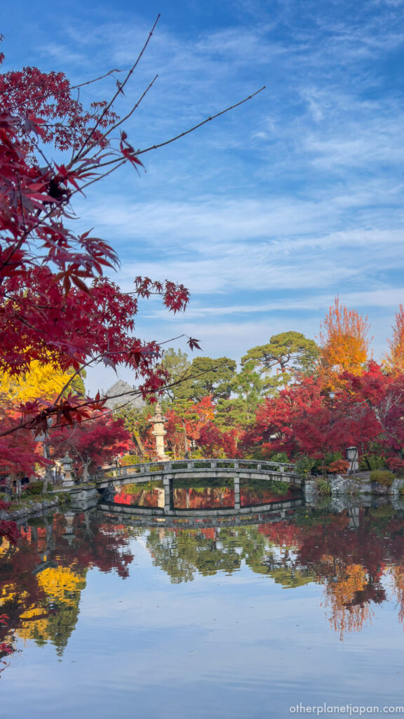 Panoramic view of autumn foliage and stone bridge over Hojo Pond at Eikando Temple, Kyoto