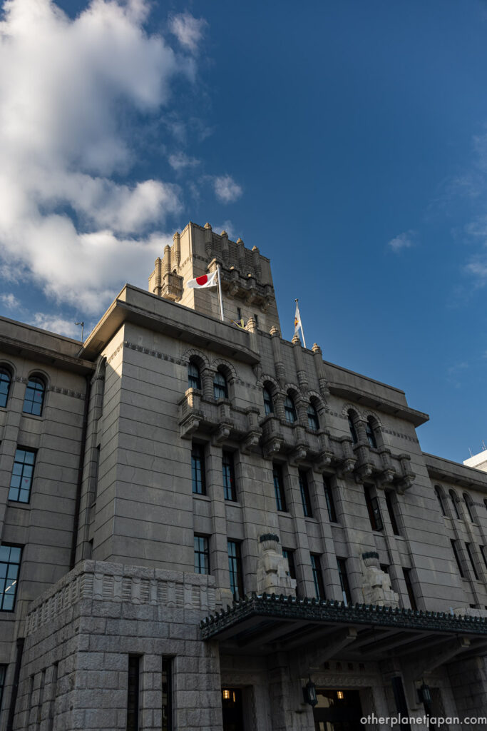The 1927 stone facade and tower of Kyoto City Hall against a blue summer sky