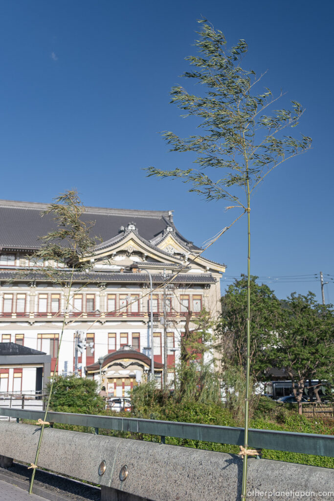 Imitake sacred bamboo standing on Shijo Ohashi Bridge with Minamiza Theater in the background
