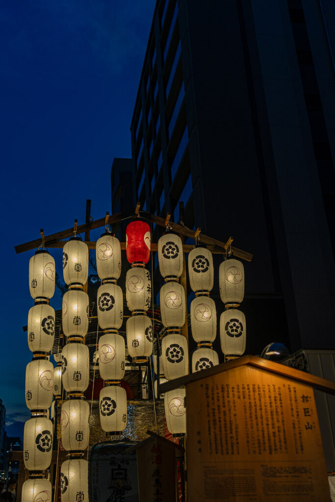 Kakkyo Yama float lanterns glowing at blue hour with its wooden history plaque during Gion Matsuri Yoiyama