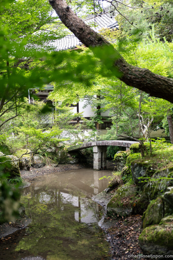 Moss-covered stone bridge reflected in a still garden pond at Bishamondo Temple, Kyoto