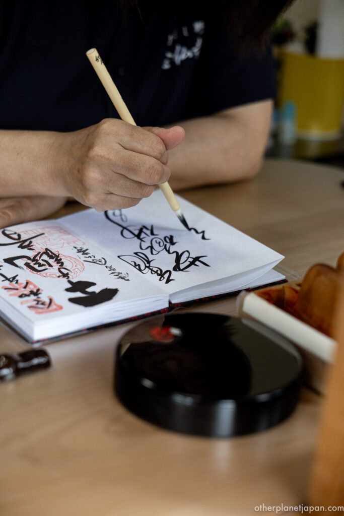Calligrapher's hands brushing a goshuin temple stamp in black ink, Kyoto