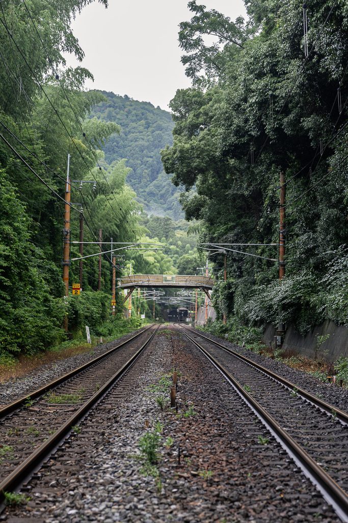 Railway tracks curving toward misty green mountains near Arashiyama in Kyoto