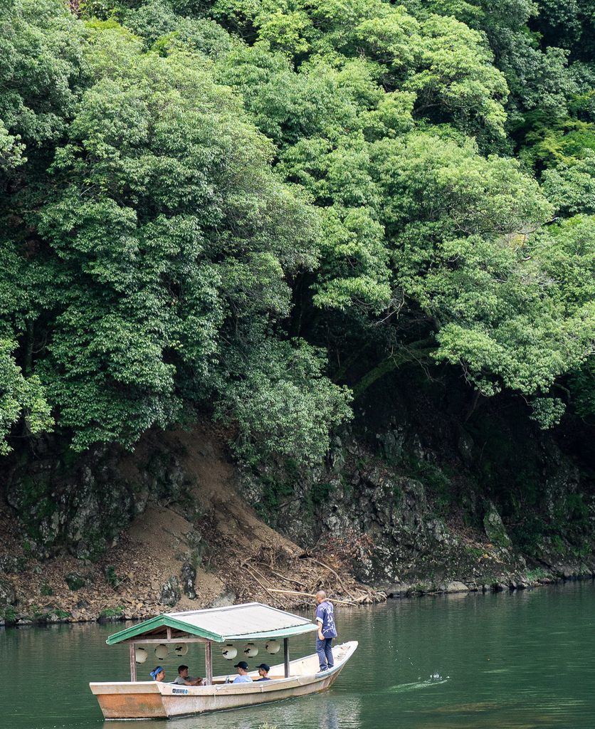 Traditional wooden boat on the emerald green Hozu River gorge near Daihikaku Senkoji Temple