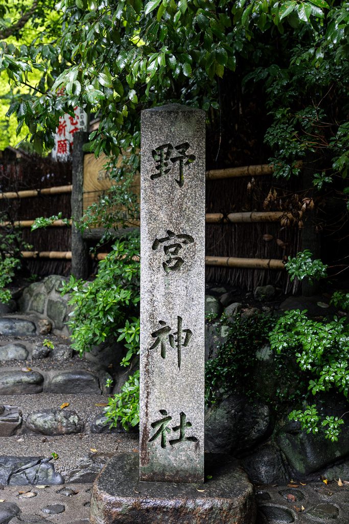 Stone pillar carved with the name of Nonomiya Shrine beside a bamboo fence
