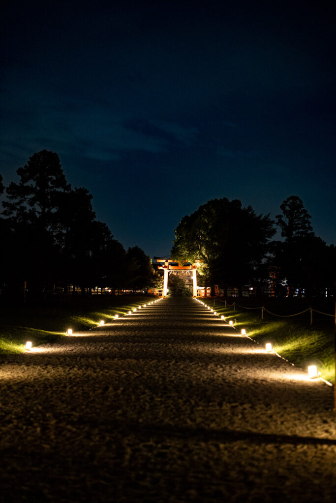 Lantern-lit gravel approach leading to the torii gate at Kamigamo Shrine during the summer night illumination in Kyoto