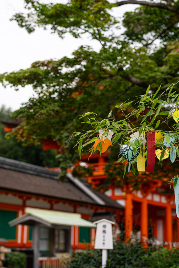 Bamboo branches with colorful paper wishes in front of the vermilion buildings of Kamigamo Shrine