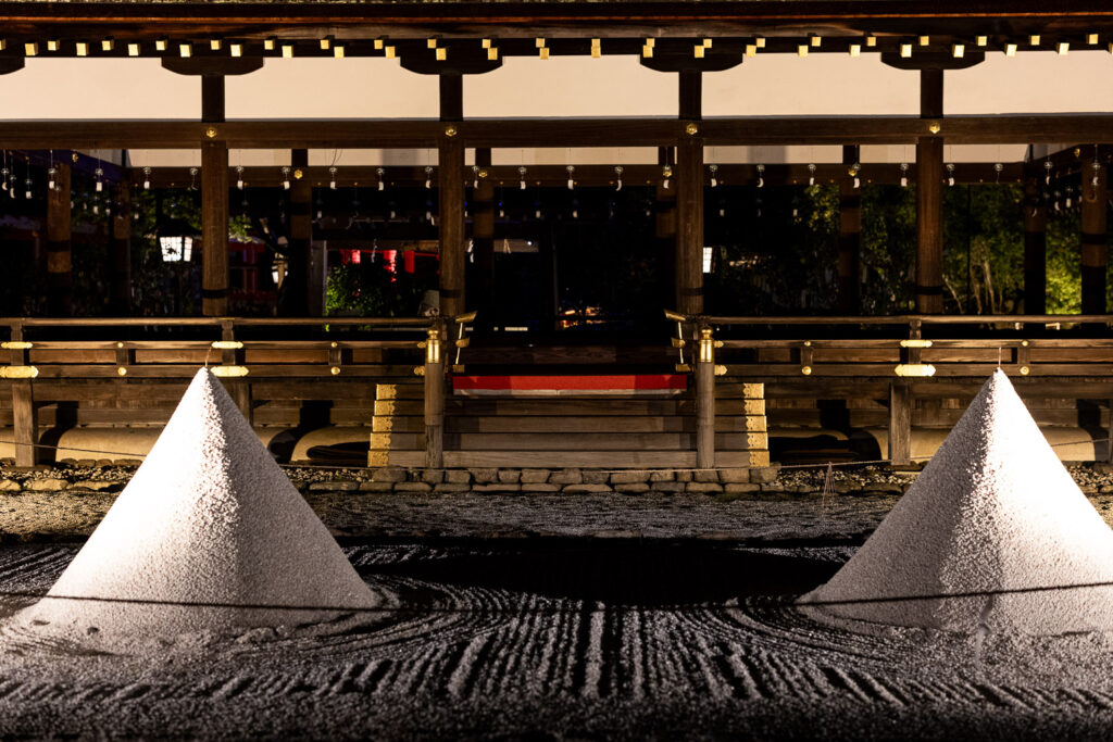 Pair of white tatesuna sand cones illuminated at night in front of the Hosodono hall at Kamigamo Shrine