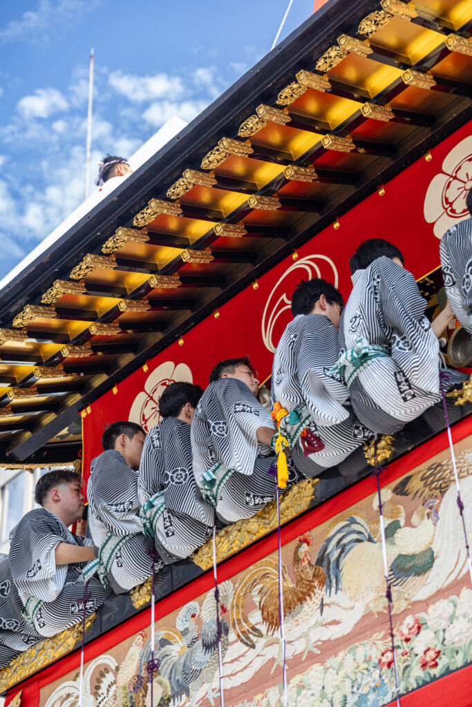 Tapestries hanging from the edge of a Gion Matsuri float above the musicians