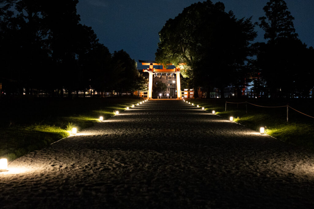 Lantern-lit gravel approach leading to the torii gate at Kamigamo Shrine during the summer night illumination in Kyoto
