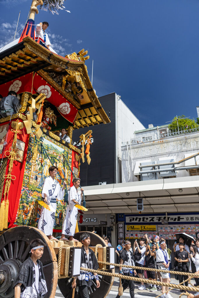 Pullers walking beside the wooden wheels of a Gion Matsuri hoko float