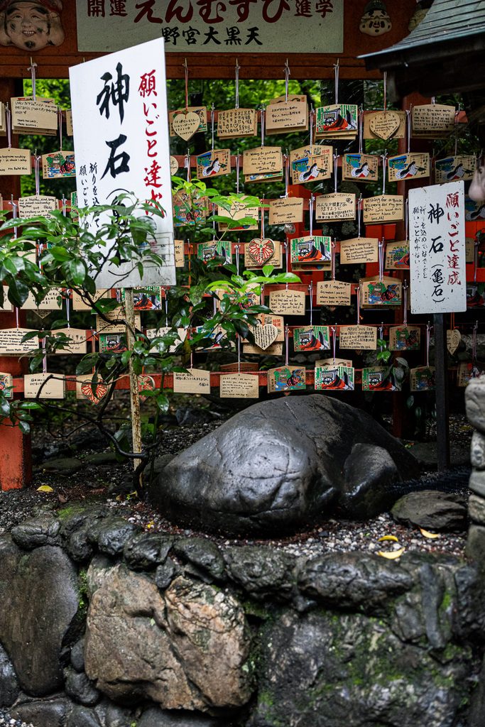 The turtle-shaped wishing stone at Nonomiya Shrine beneath rows of wooden ema plaques