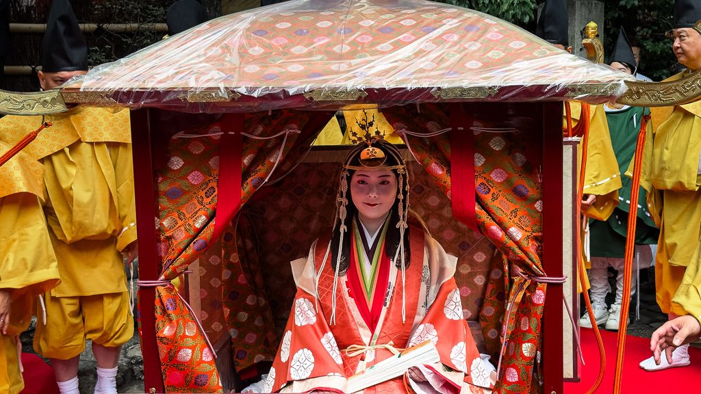 A woman in Heian-period court dress seated in an ornate palanquin during the Saigu Gyoretsu