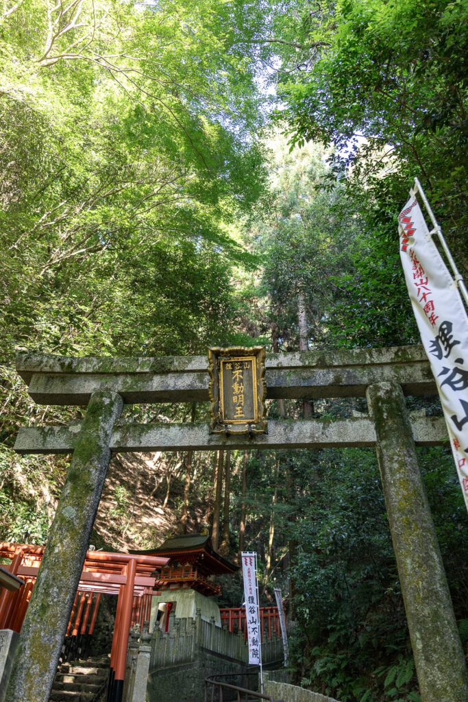Stone torii gate with a gold plaque reading Tanukidani-san Fudo Myo-o at the entrance to Tanukidani Fudoin temple in Kyoto