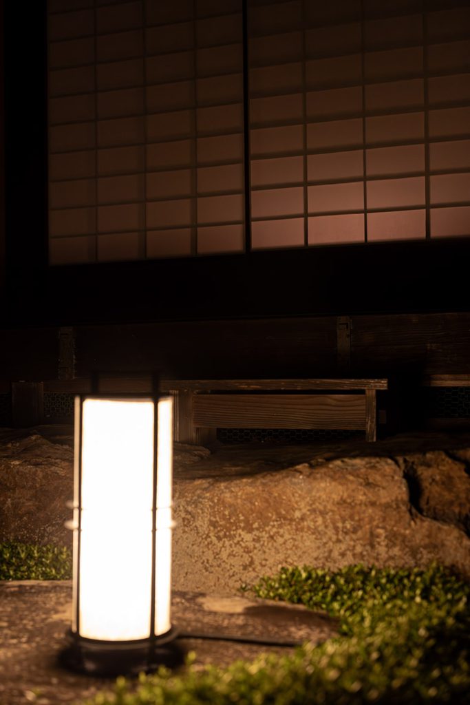 Paper floor lantern glowing orange in front of shoji screens at Shoren-in Temple at night