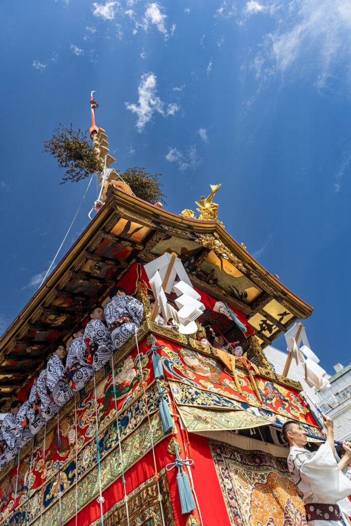Looking up at a Gion Matsuri float's gilded roof against a blue July sky