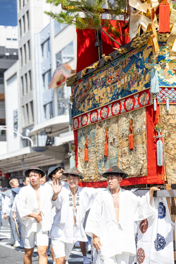 Float bearers in white robes and straw hats under the July sun at Gion Matsuri