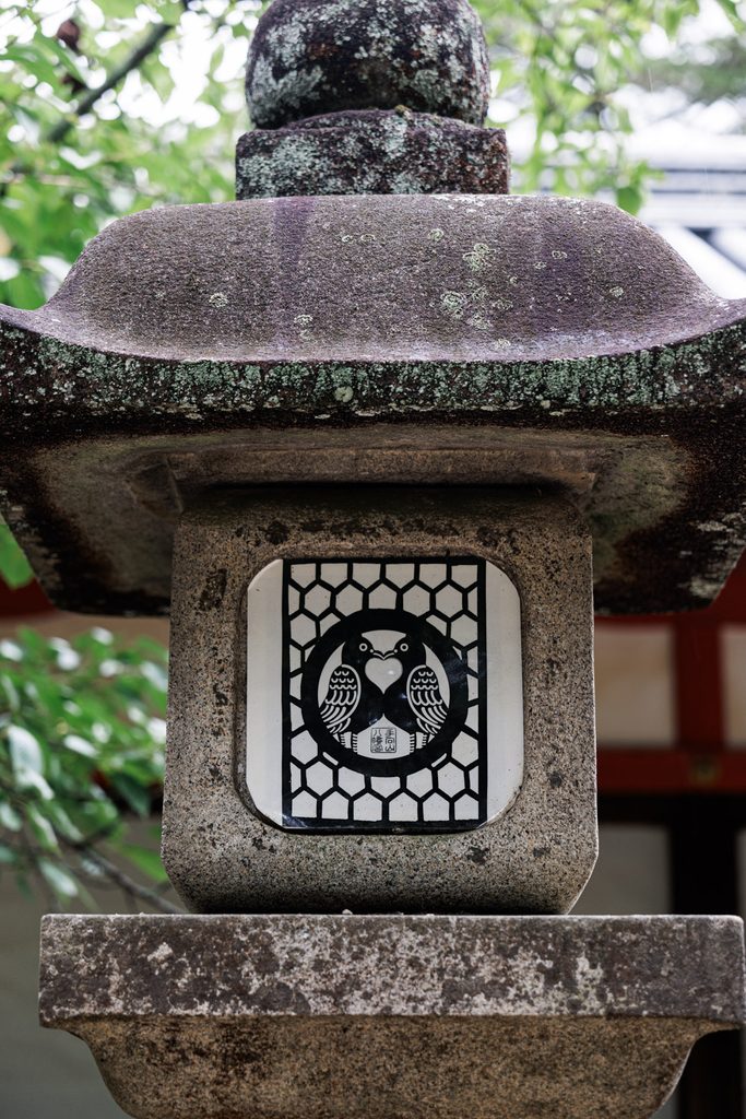 Two-dove crest forming a heart shape on a stone lantern at Tamukeyama Hachimangu Shrine