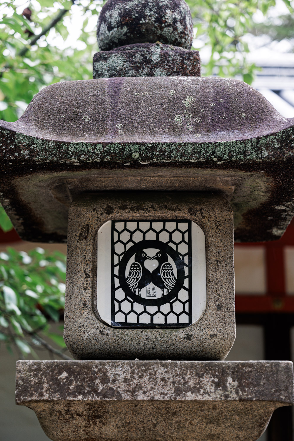 Two-dove crest forming a heart shape on a stone lantern at Tamukeyama Hachimangu Shrine