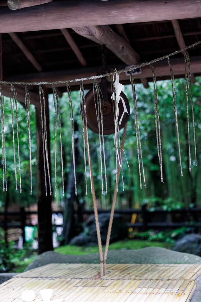 Paper streamers and a straw rope hanging in the still morning air at a Shinto shrine in Arashiyama