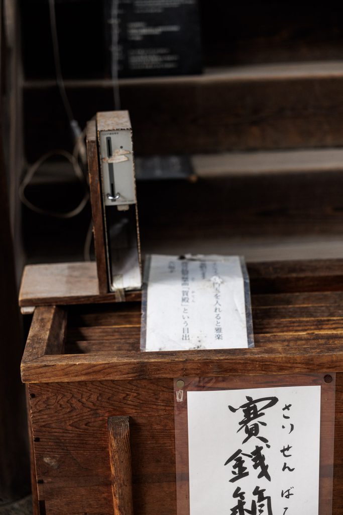 The wooden offering box at Himuro Shrine with the coin-operated gagaku music player beside it