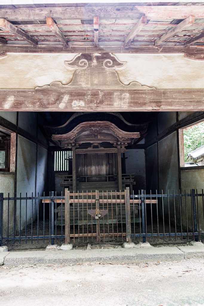 Weathered Toshogu shrine behind a rusted iron fence at Tamukeyama Hachimangu Shrine