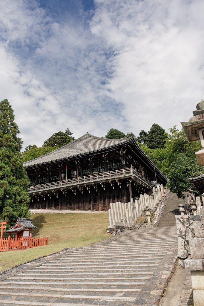 Stone steps leading up to Nigatsudo at Todaiji, with the wooden hall and its lanterns against a summer sky
