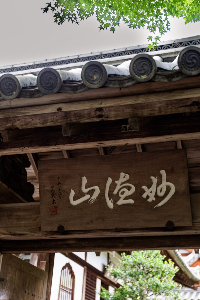 Wooden plaque reading Myotokuzan hanging at the gate of Suzumushi-dera Temple in Kyoto