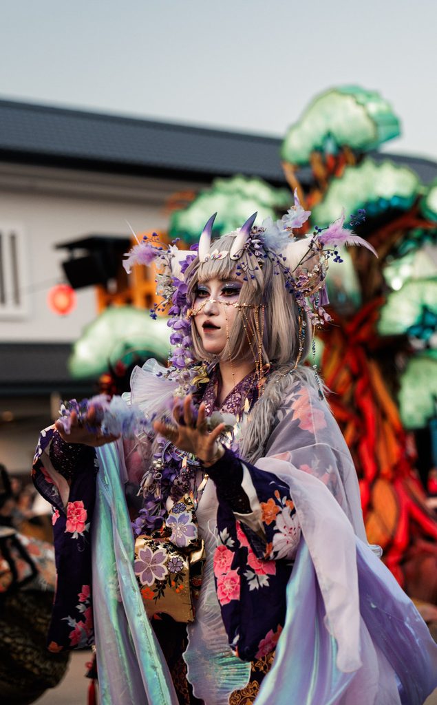 Performer with purple horns and wisteria in her hair at the Kaikai Yokai Festival