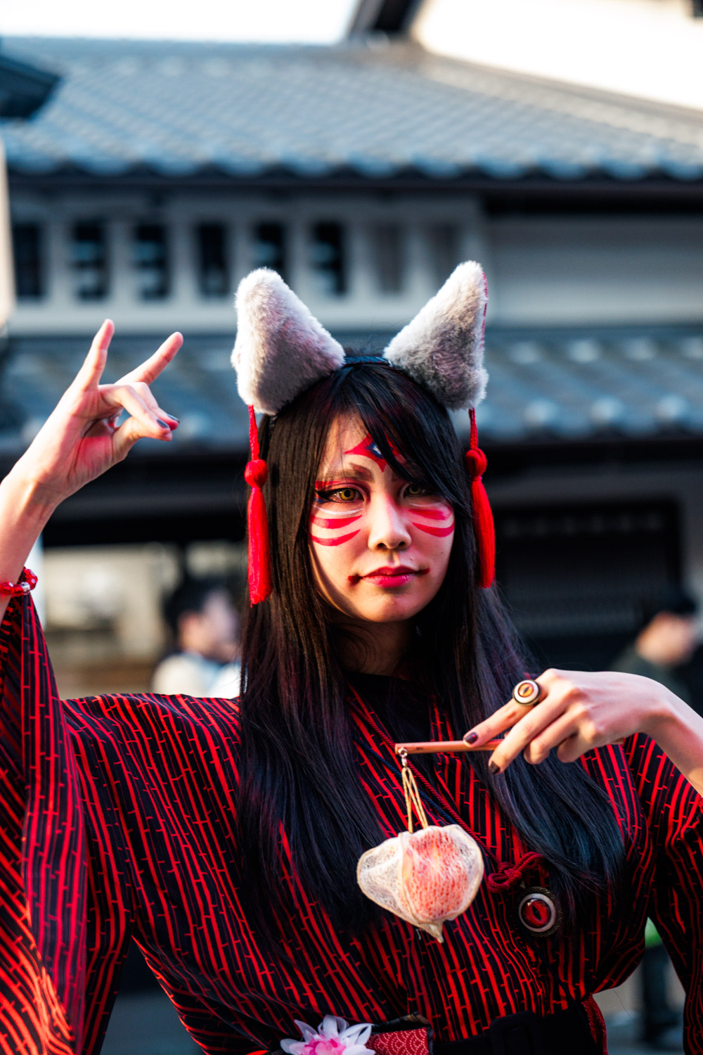 Performer in fox yokai makeup and ears on an Edo-style street